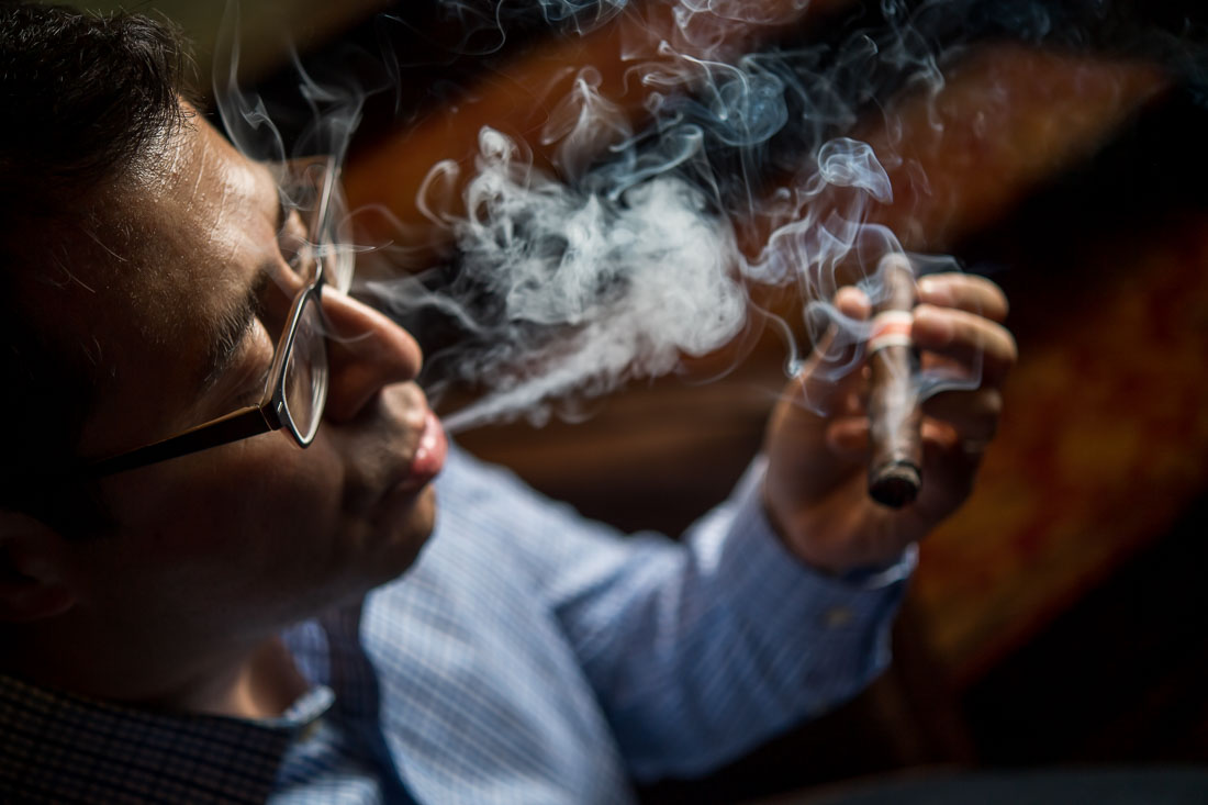 NYC Branded Lifestyle Portraits Cigar Merchant Luis Paredes puffing out a big cigar smoke
