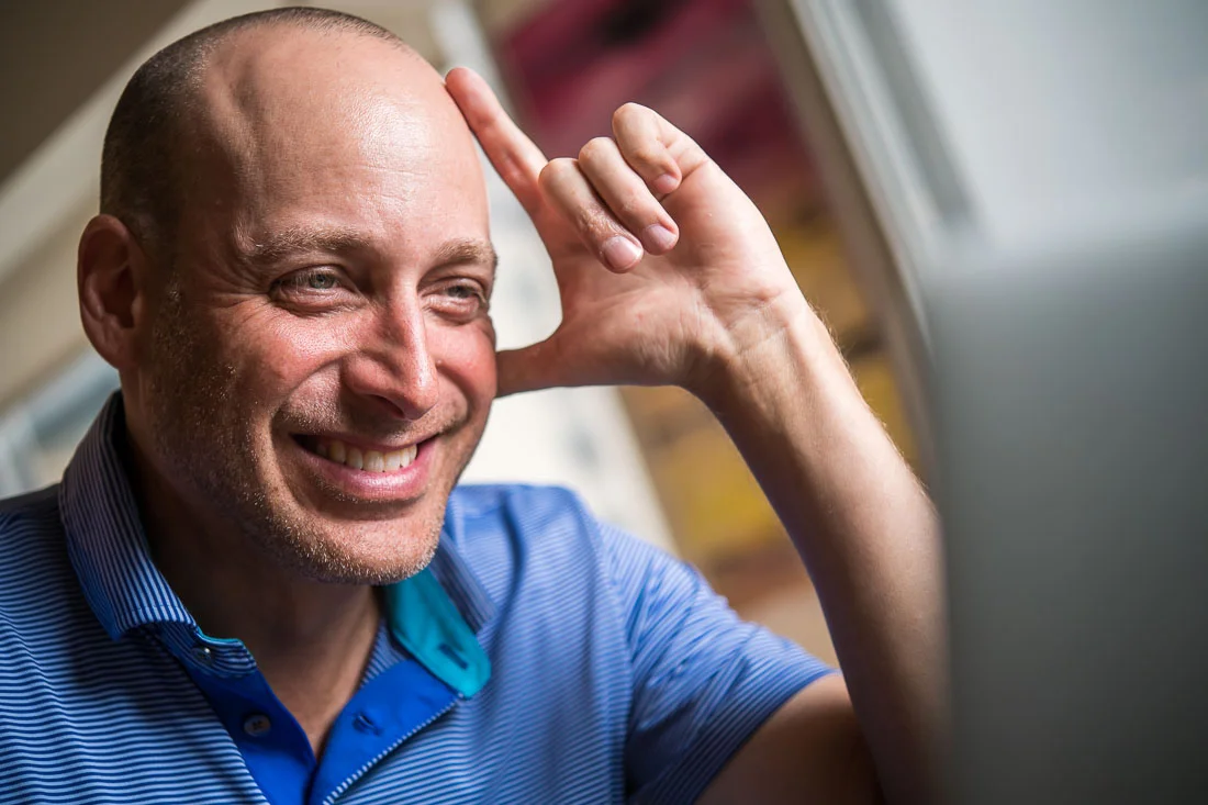 NYC Branded Lifestyle Portraits Speaker Thrive Lou Diamond smiling while looking at computer