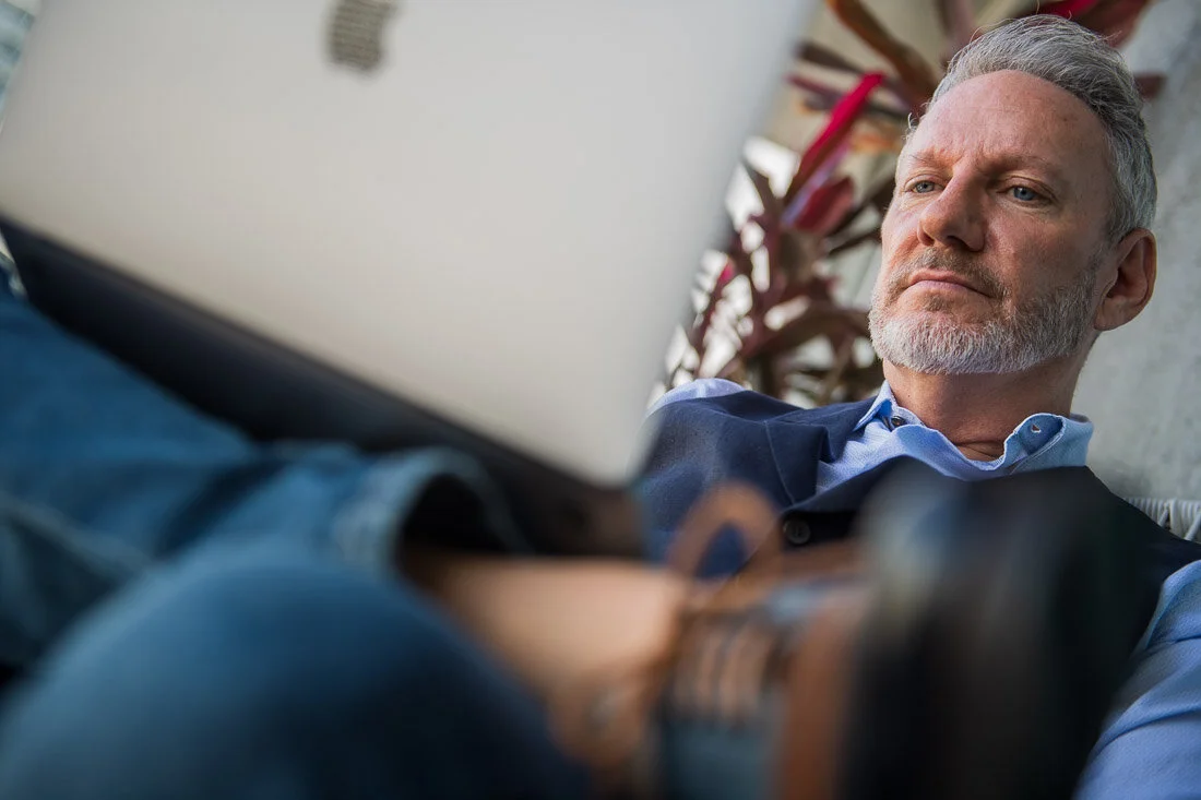 NYC branded lifestyle portrait Speaker Lingo Author Jeffrey Shaw intently working on his laptop on balcony