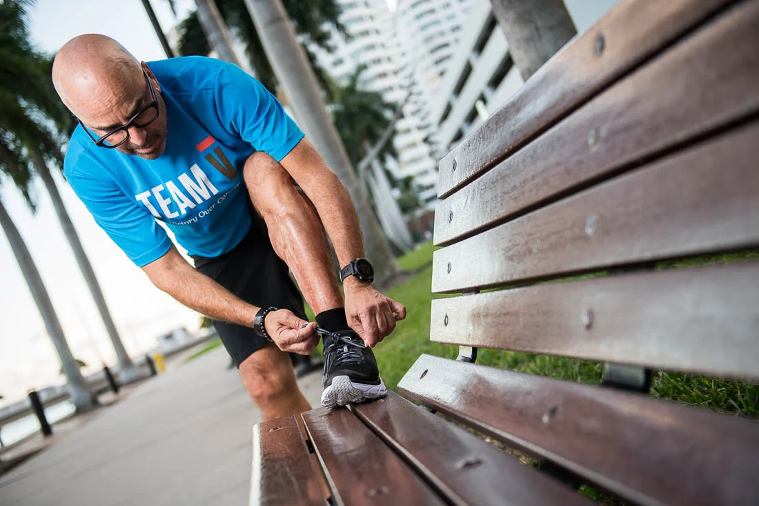 NYC Branded Lifestyle Portrait Howie Doin It Howie Kra tying shoelace on bench in Miami Beach