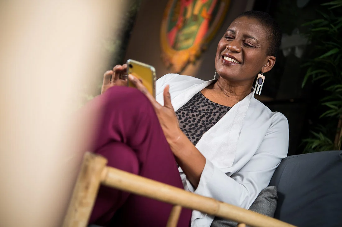 NYC branded lifestyle portrait Speaker Author Denise Jacobs smiling while reading her phone