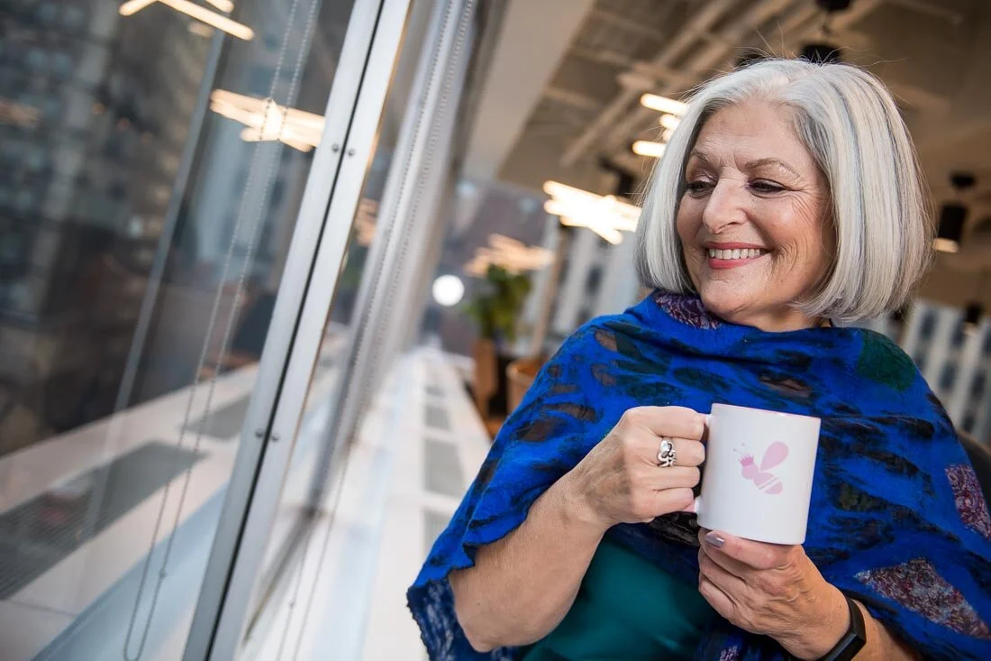 NYC Personal Branding Photography Speaker Trainer Janet Neal looking out window holding coffee cup