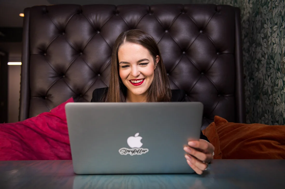 NYC personal branding photo Speaker Author Melanie Deziel working on laptop smiling