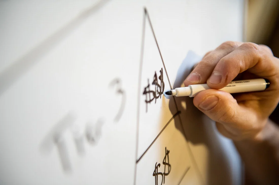 NYC Personal Brand Photography Webinar Consultant Joel Erway writing dollar signs on whiteboard