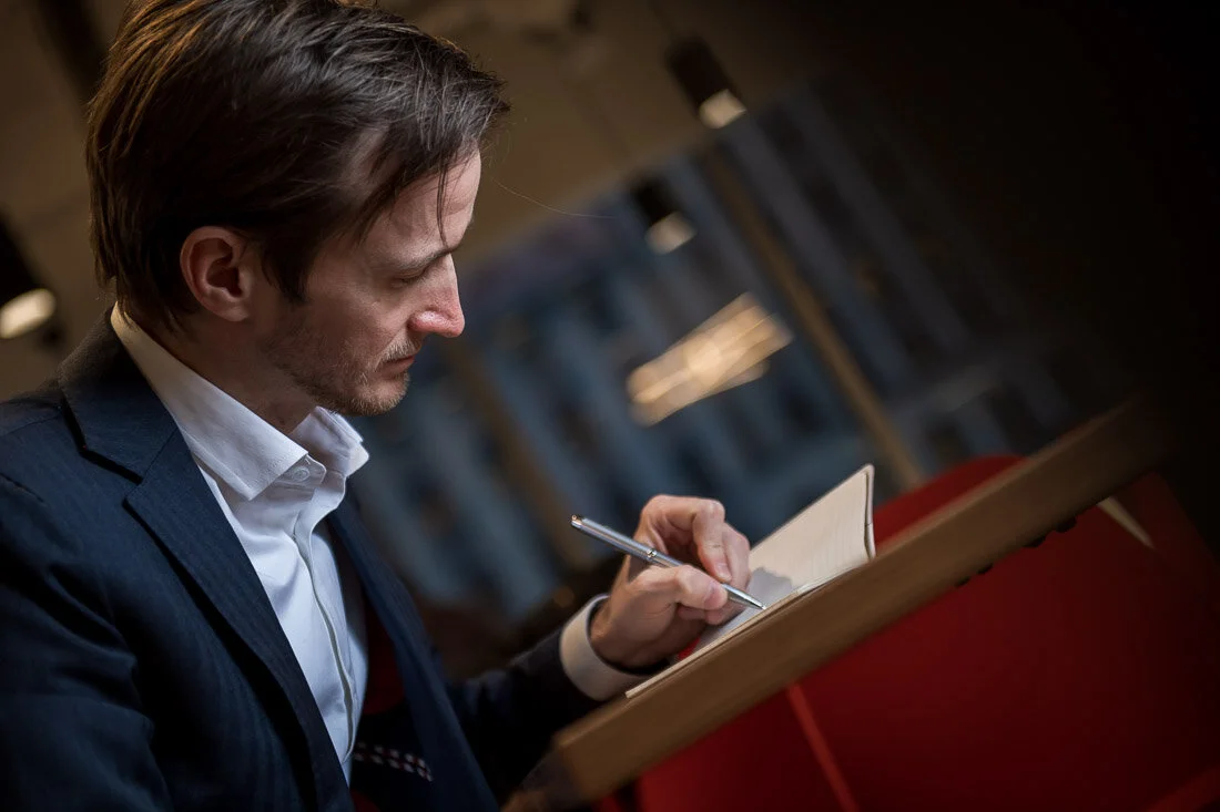 NYC Personal Branding Photography Humorist Drew Tarvin brainstorming an idea while writing in notebook