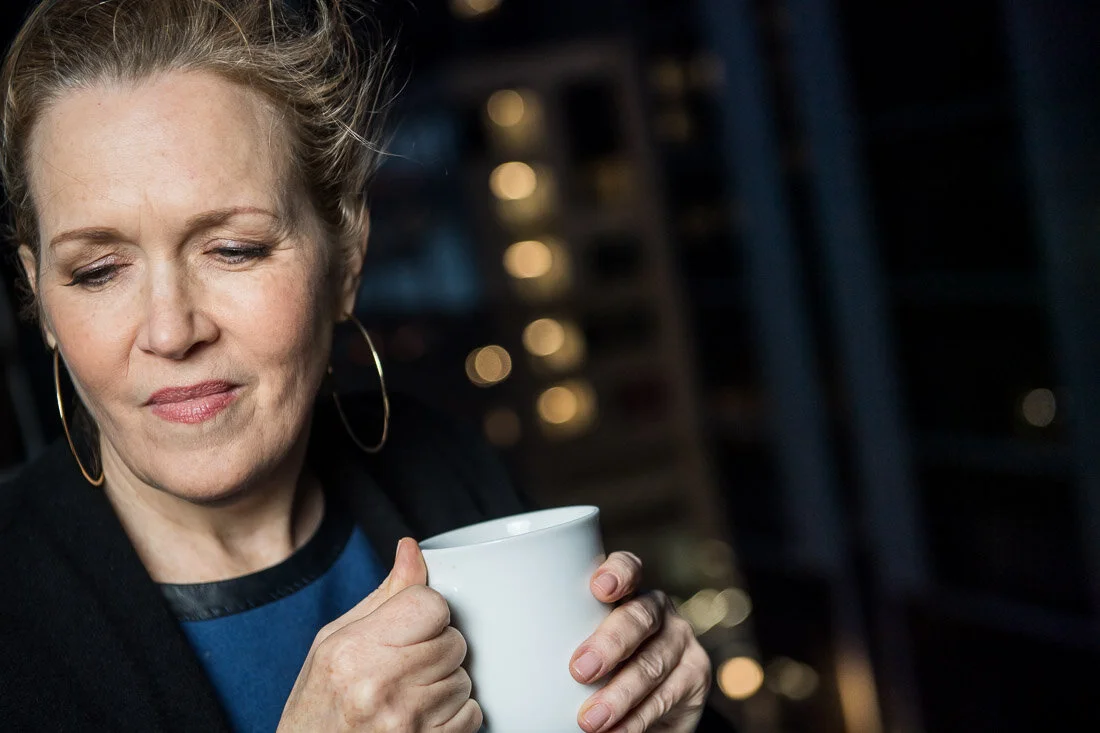 NYC personal branding photography Speaker Facilitator Jeanne Stafford thinking to herself with coffee cup on ledge