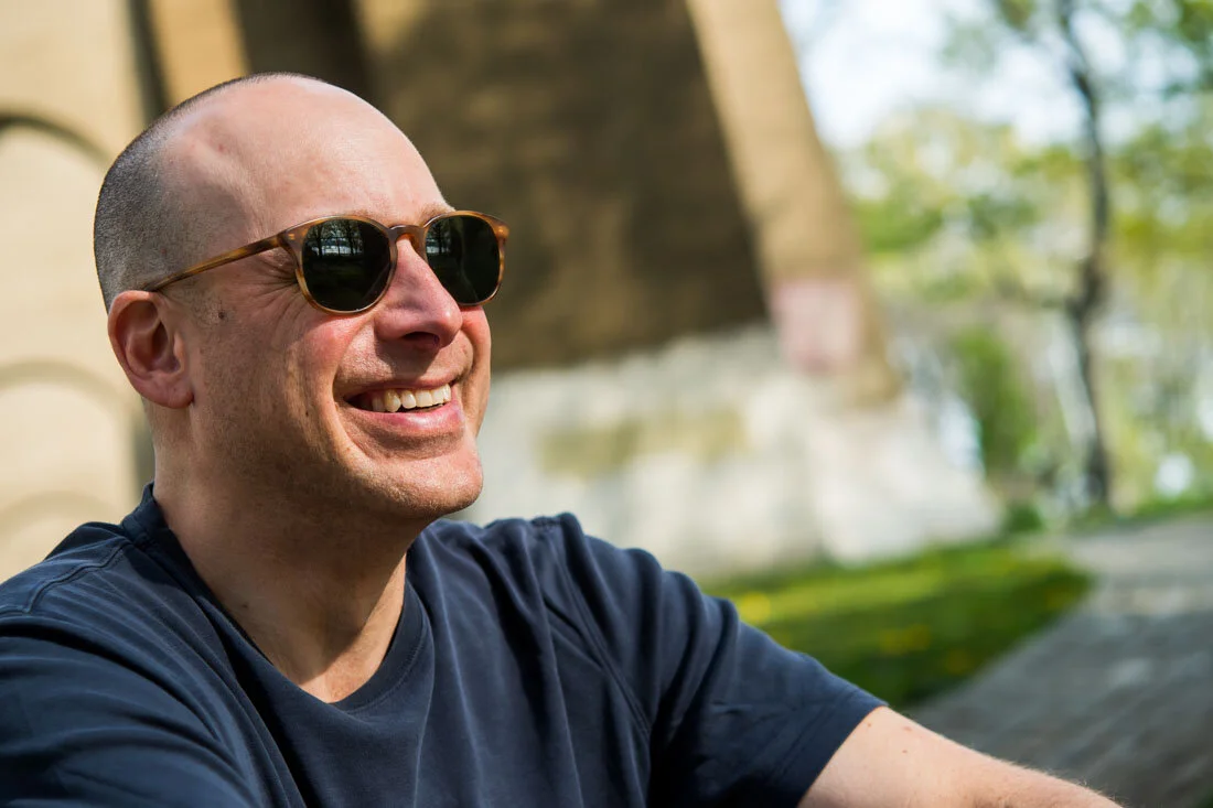 NYC Branded lifestyle portrait Speaker Lou Diamond sunglass on and smiling in park