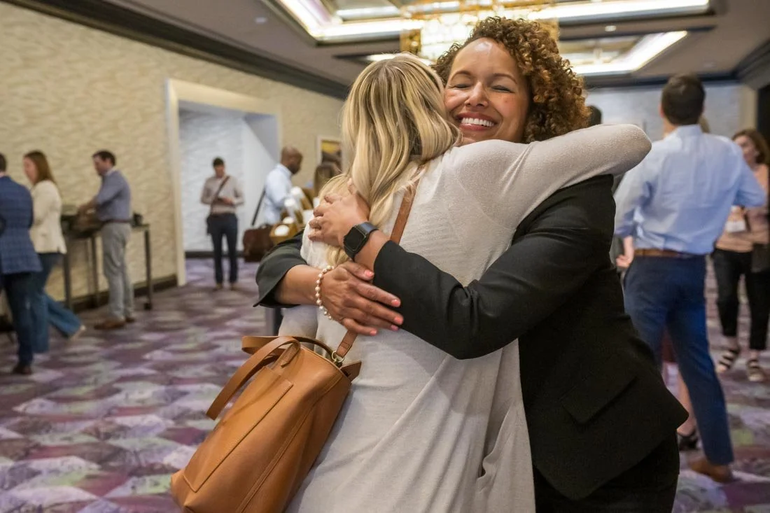 live event photo Speaker Author Heather R Younger hugging participant after keynote