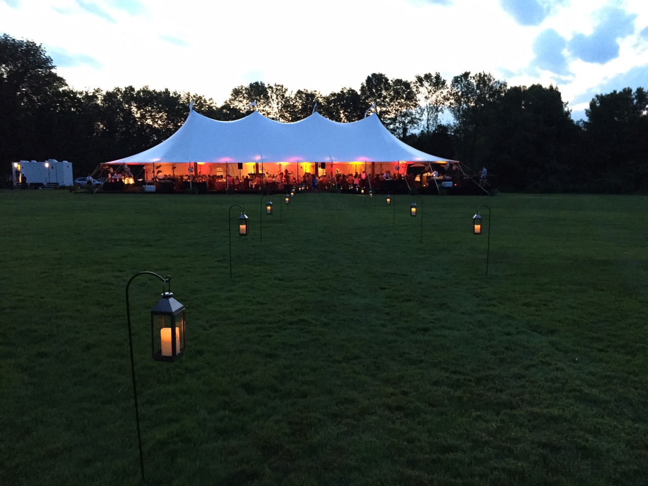 The view from the walkway to the tent entry at dusk, with amber uplighting in the tent