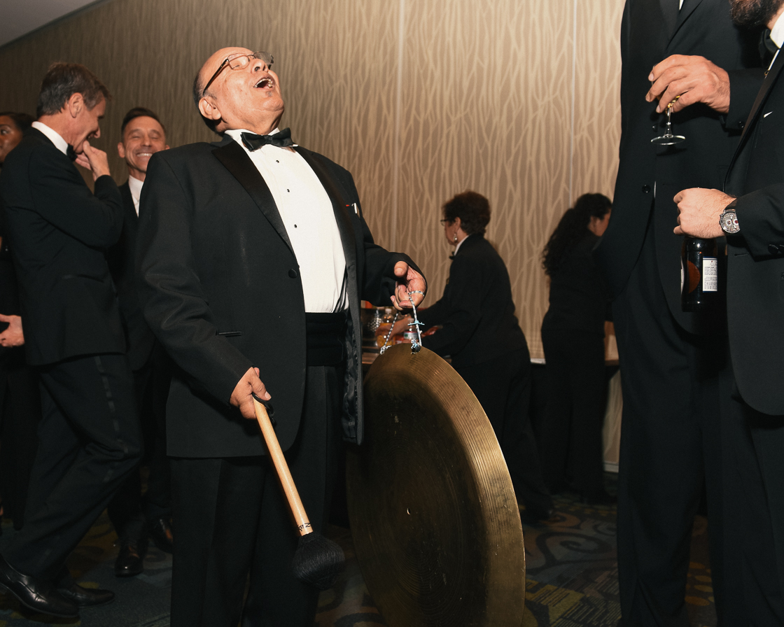 Lolo Villagomez strikes the gong that signals to guests that dinner is served in the ballroom. To his right is a guest that was almost 8 feet tall.