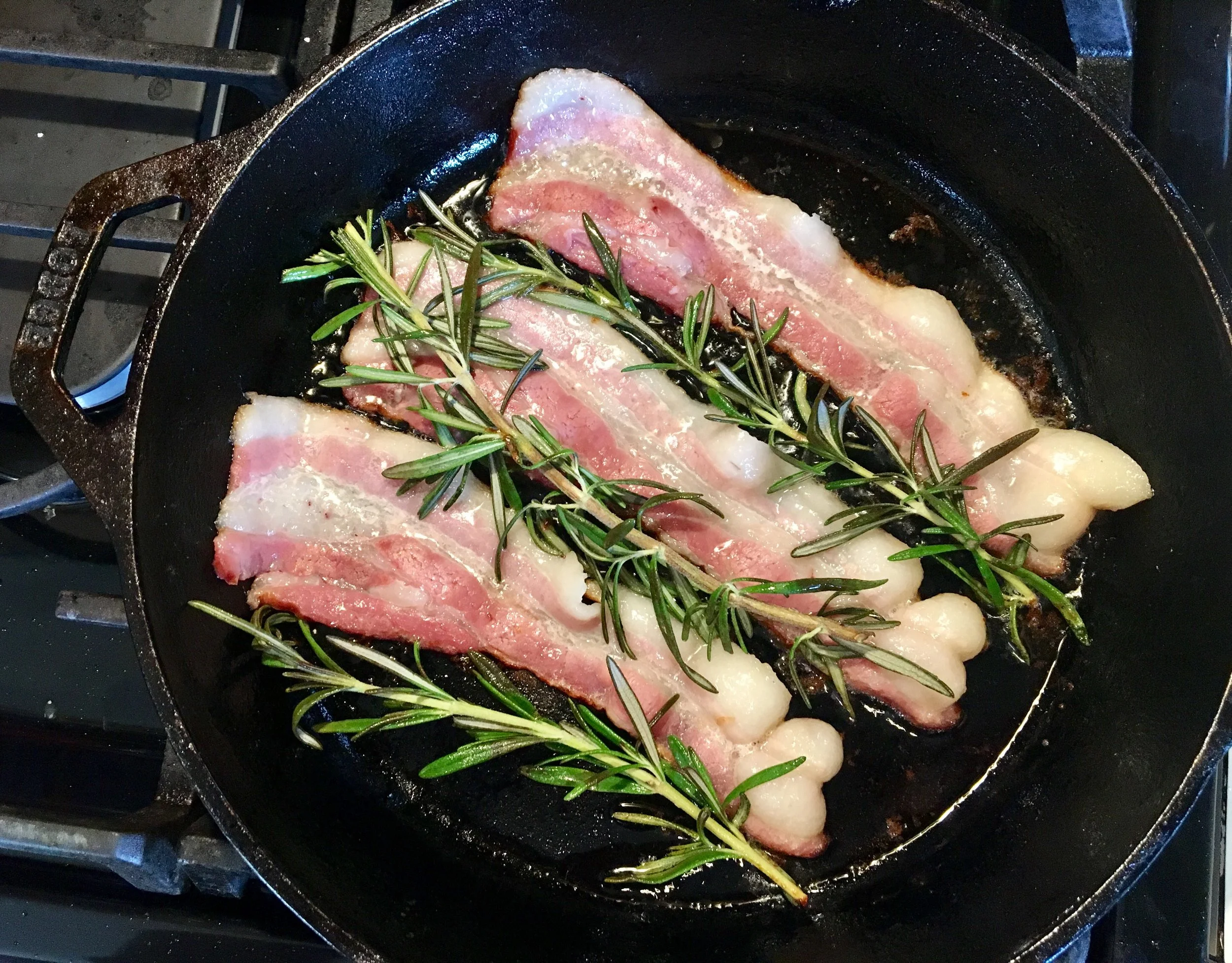 Pan frying Oklahoma produced Berkshire Bacon with fresh rosemary 