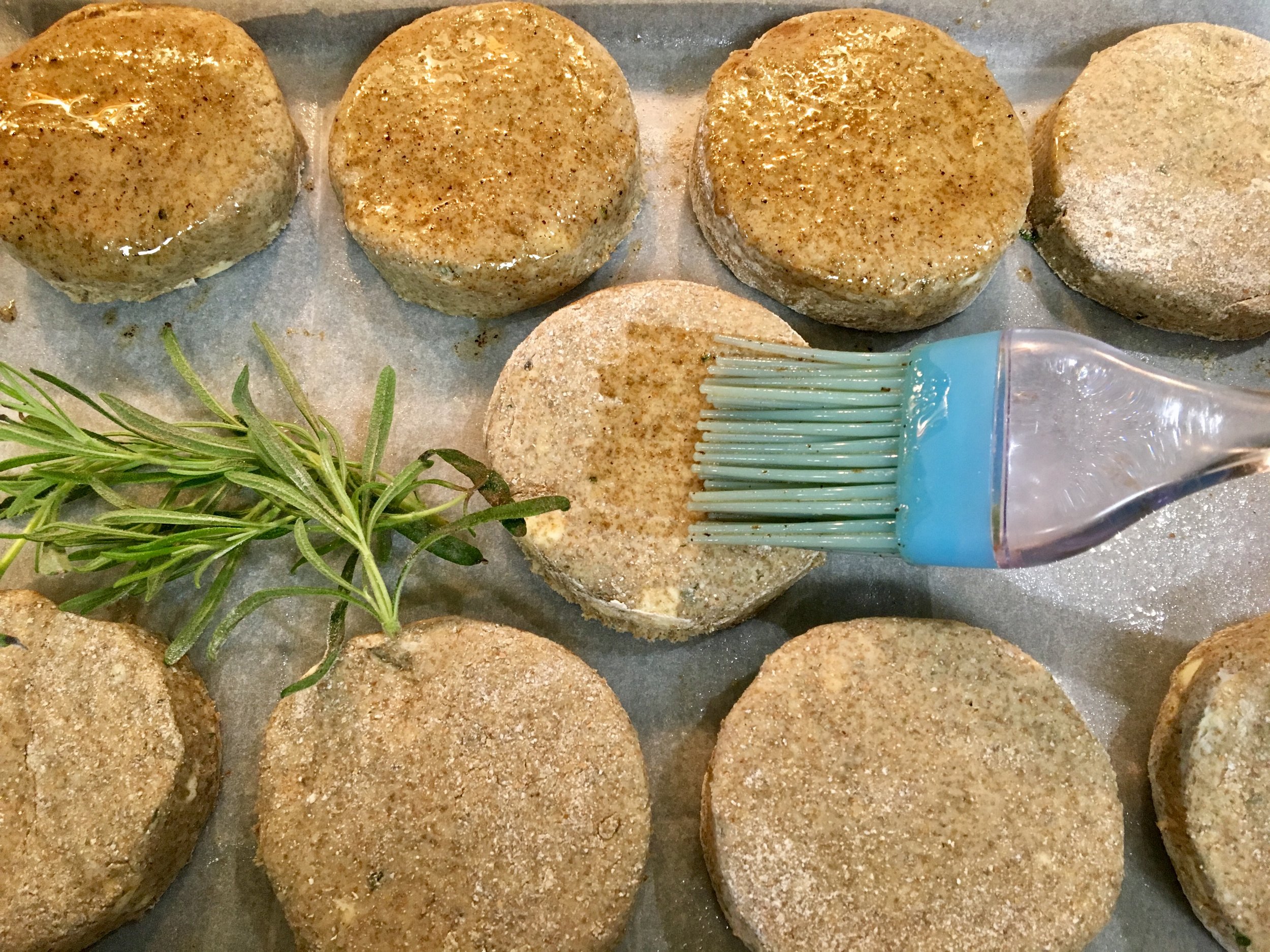 Brushing the tops with butter before heading to the oven. 