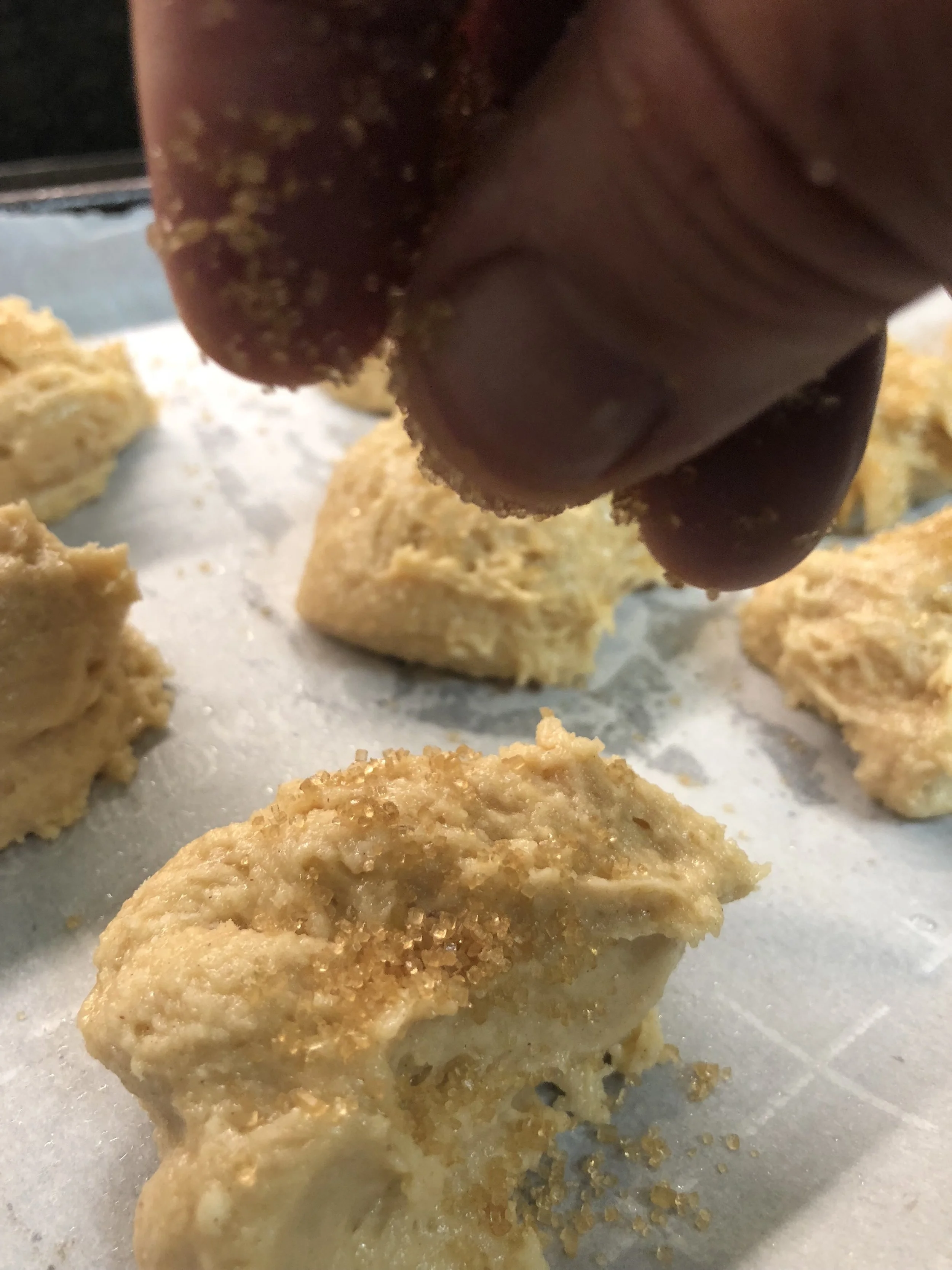 Sprinkling the tops of the spiced shortbread with crunchy turbinado sugar.