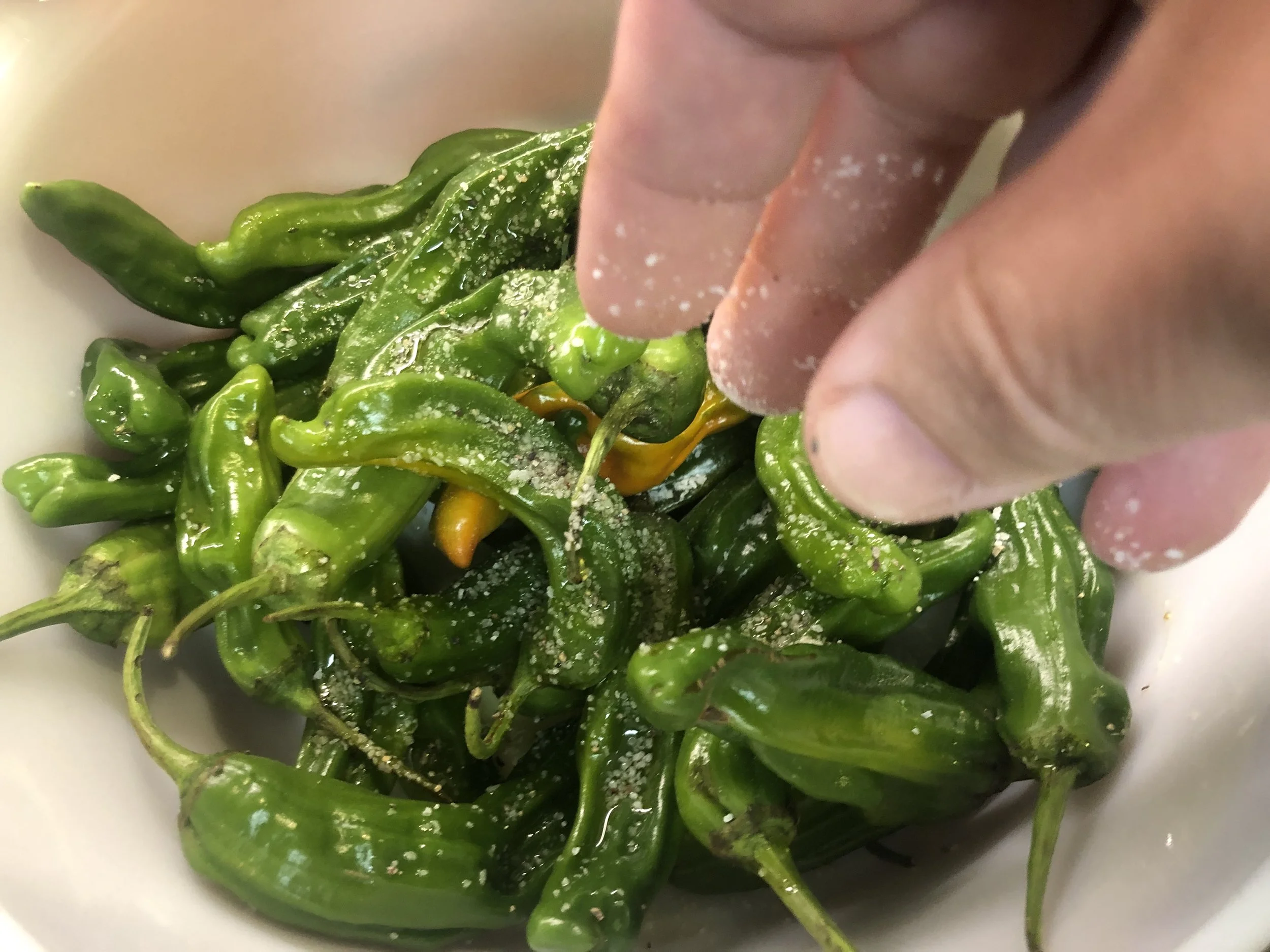 Fresh shishito peppers tossed with olive oil and Cook’s Line Seasoning before grilling.