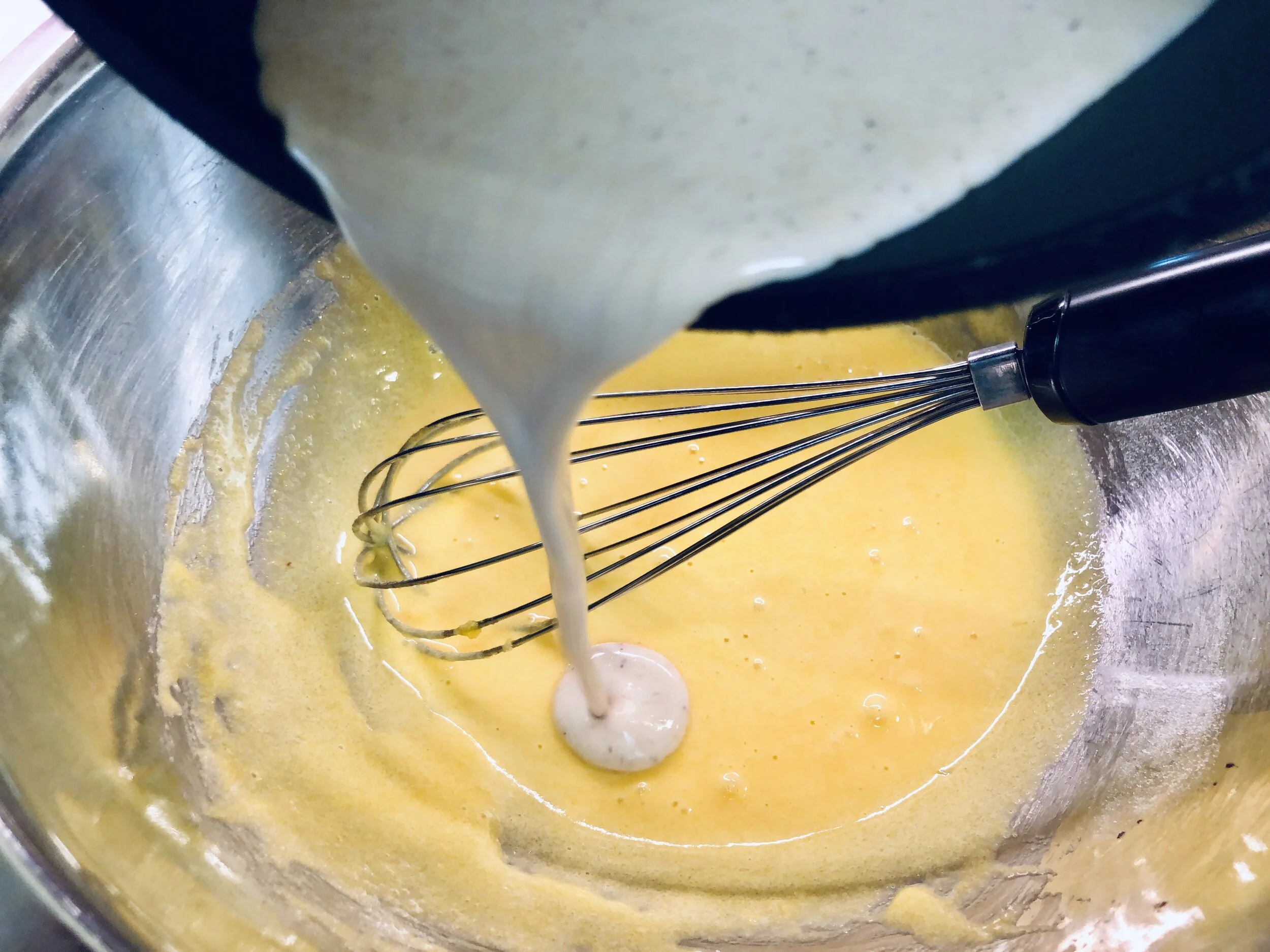 Tempering the hot milk into the egg mixture