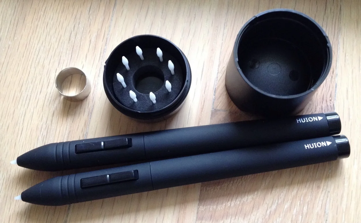 Eight replacement nibs and an extractor ring are tucked inside the pen stand. The pens have a nice rubberized finish and two buttons.