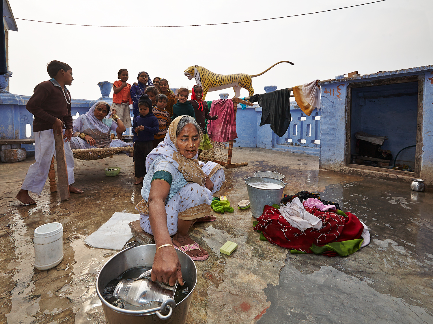 The lady of the household poses for a photo while another lady is taking care of the laundry