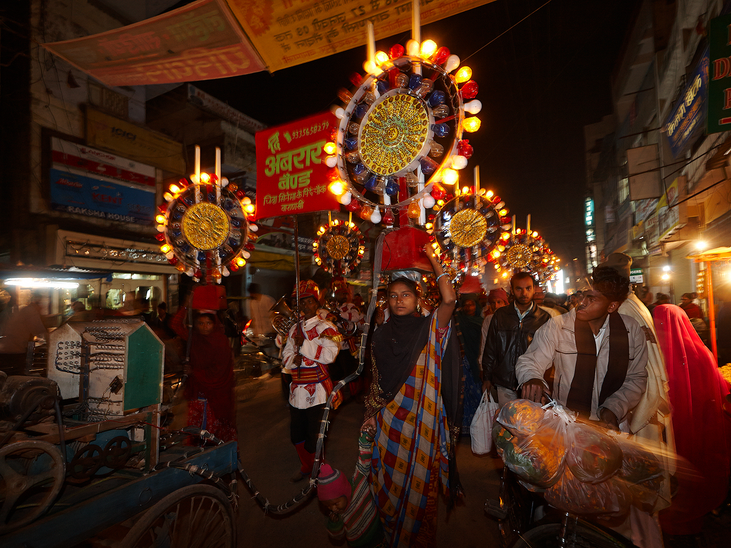 The Light-Bearers walking a marriage procession. On of the bearers has a toddler who she had to bring along with her