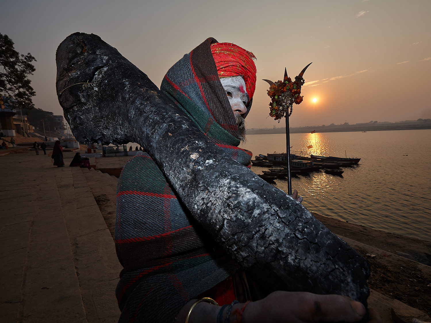 A Sadhu carrying back a log from the burning ghats that he will use for warmth during the winter months.