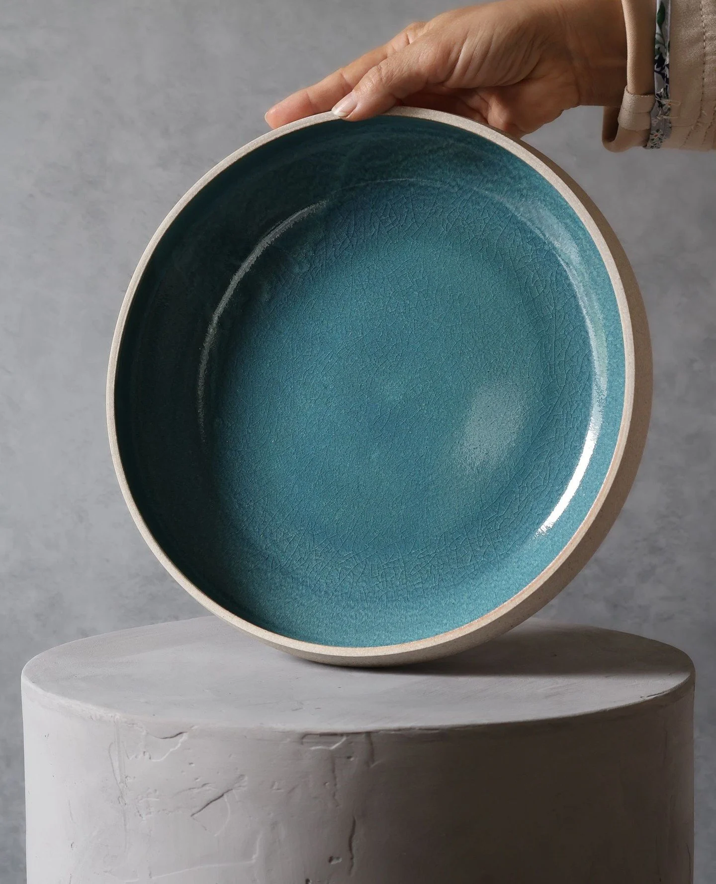 Stoney weight below, glossy depth within.⁠
⁠
A low, wide bowl with angled walls and a quiet exterior&mdash;unglazed, half porcelain, half stoneware. The interior holds a different story: a glossy, deep blue (with a hint of green) that shifts with the