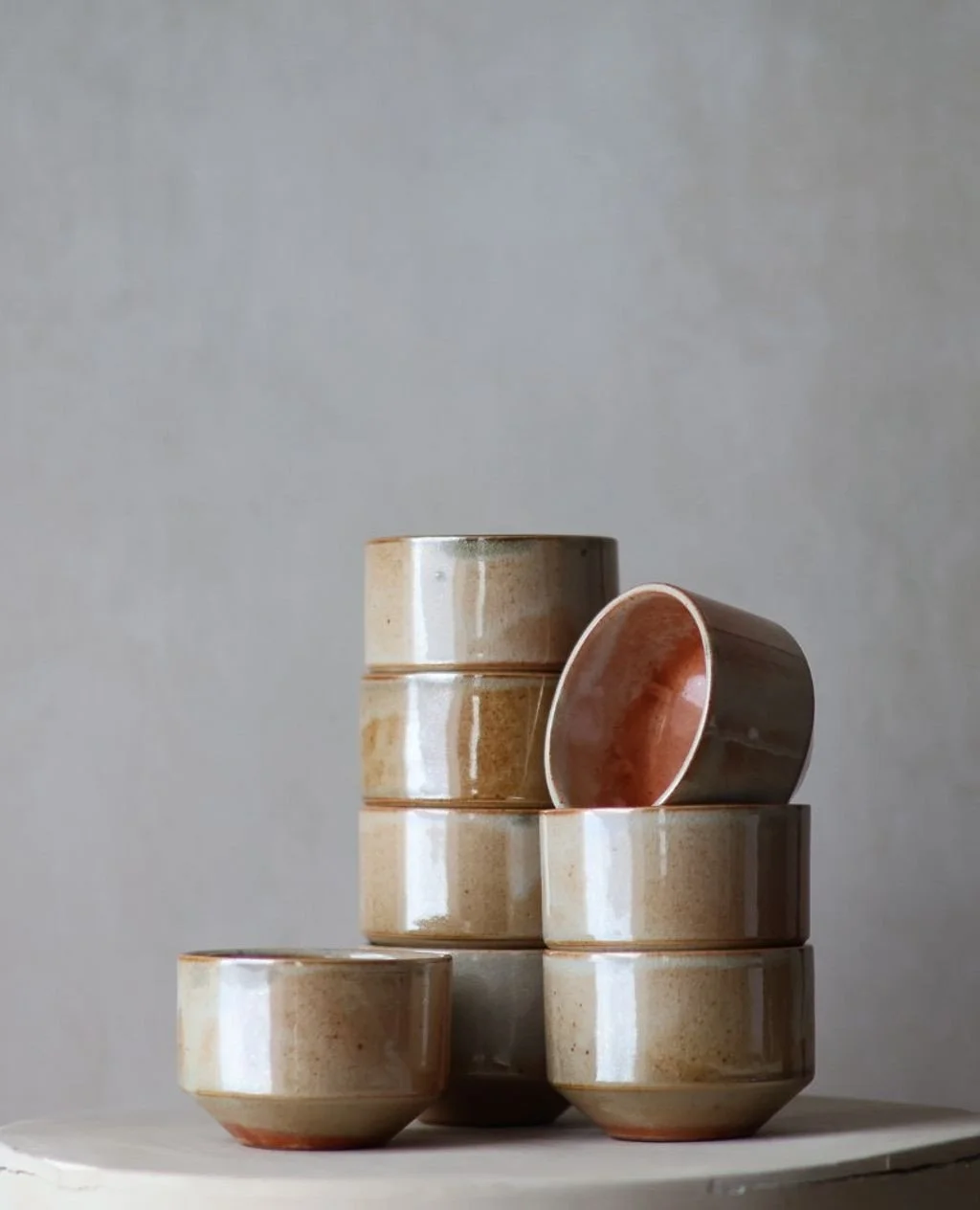 These warm Shino cups sit in a different position than yesterday's green. These are lighter atmosphere, less soot, more flux. The iron in the glaze shifted warm instead.⁠
⁠
The range is both surprising and more of the same. Sage. Peach. Deep caramel.