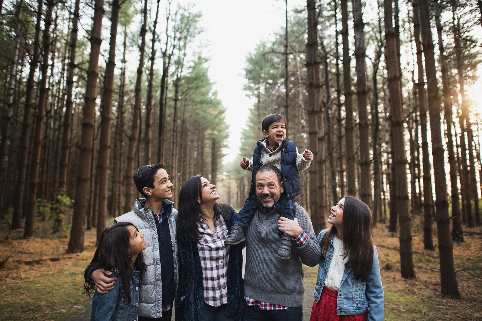 family on wooded path with son on dads shoulders smiling laughing by kellie bieser.jpg