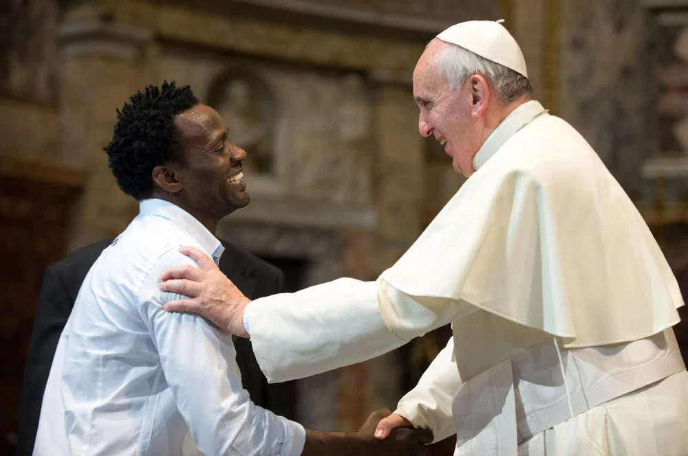 Pope Francis greets a refugee during a mass in the Church of the Gesu in Italy.