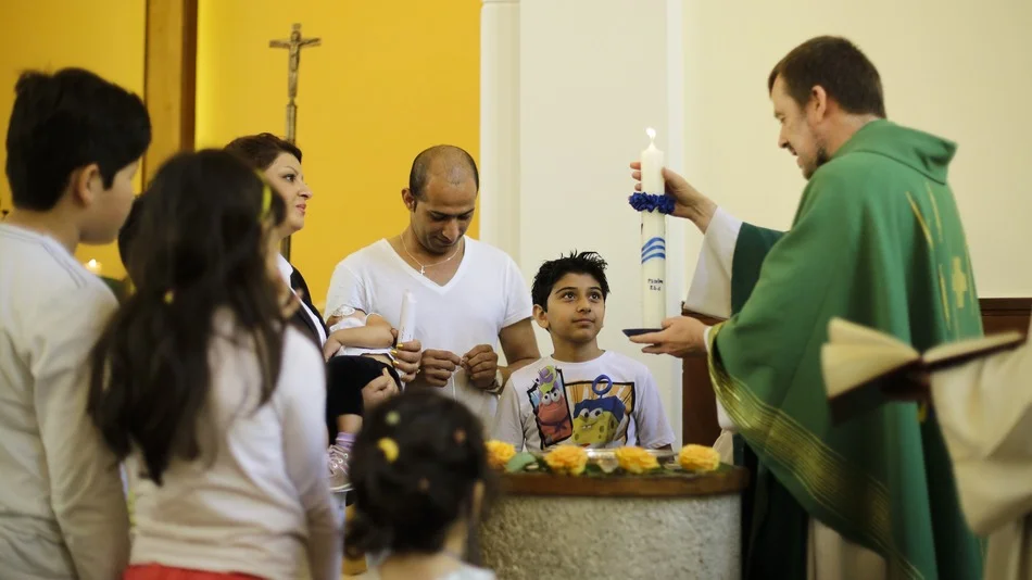 Pastor Gottfried Martens lights a candle during a service to baptize people from Iran, in the Trinity Church in Berlin. Third right is Iranian asylum-seeker Mohammed Ali Zanoobi. He is one of hundreds of mostly Iranian and Afghan asylum seekers who have converted to Christianity at the evangelical church. (Image: Markus Schreiber/AP)
