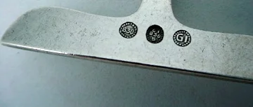This is an example of the Classic GI marking inside a circle of beads (used from 1915-1930), as well as the .830 mark used before 1927, denoting the 83% silver content used before going to the sterling standard. Also present is the GI 830S mark as well. Often earlier pieces could be stamped multiple times.