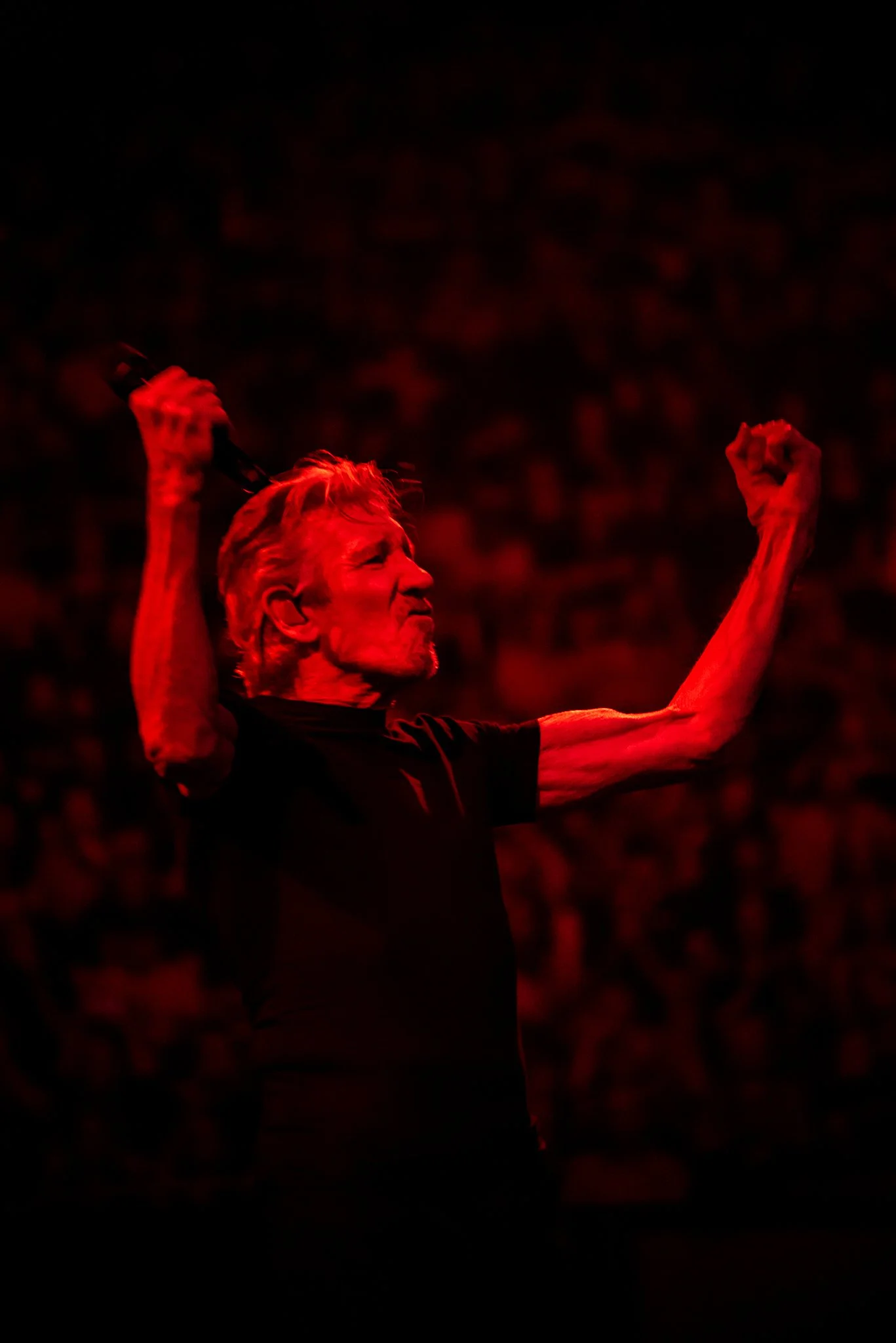 Roger Waters of Pink Floyd in a red glow of overhead light.