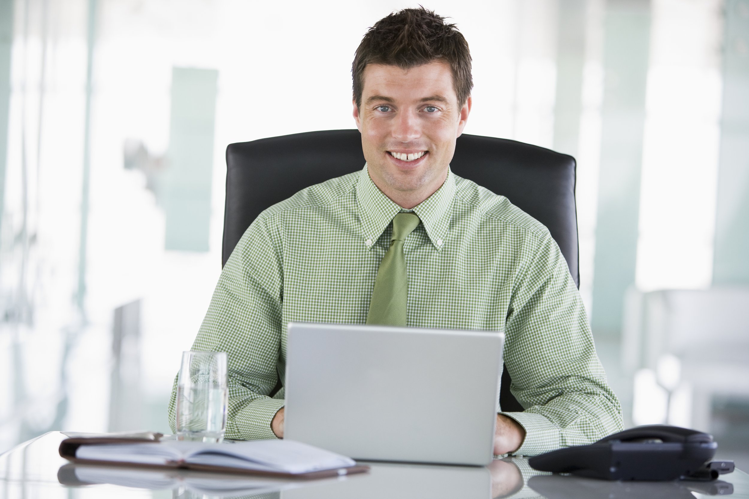 businessman-sitting-in-office-with-personal-organizer-using-laptop-smiling-SBI-301023004.jpg