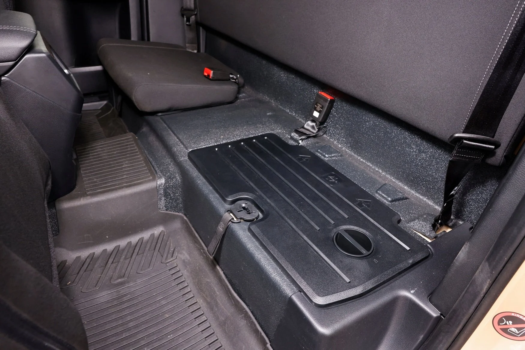 Seat base removes for flat stowage and a tie down tether to restrain the load