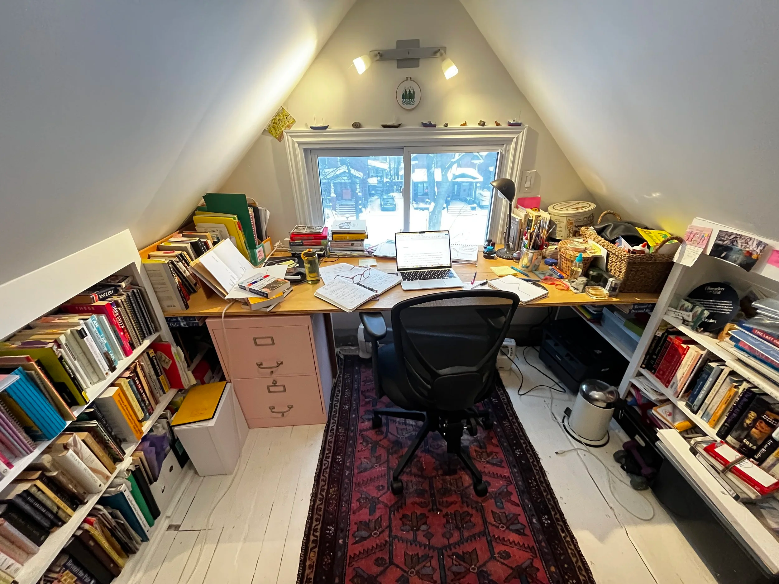 Desk and chair in attic with bookshelves on either side.