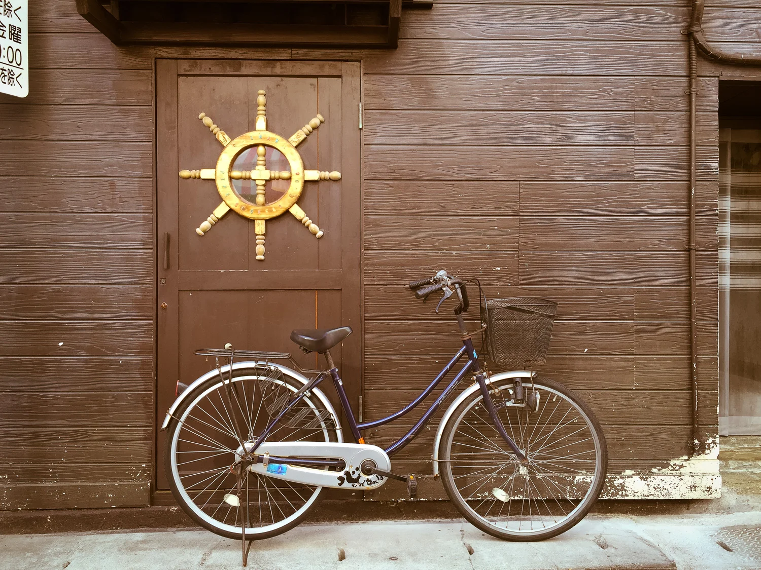 This bicycle parked next to a brown wood building really caught my eye. Naha, Okinawa, Japan. Apple iPhone 6 Plus at ISO 32, f2.2, 1/160 sec.