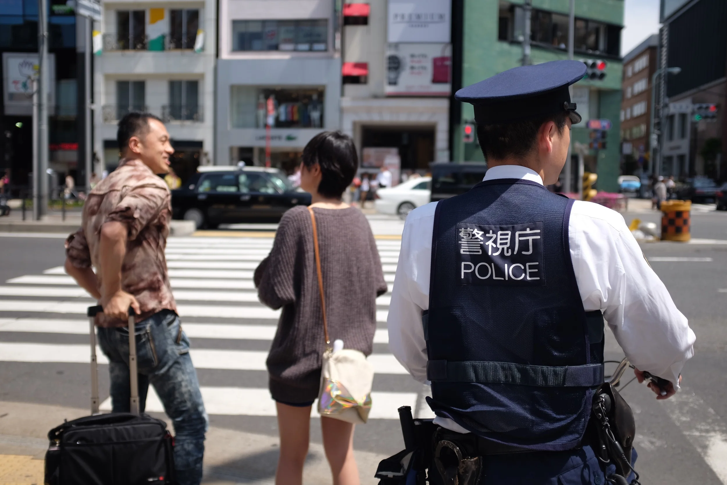 A policeman waits to cross at Aoyama dori near Omotesando station, Tokyo. Fujifilm x100t, ISO 200, f/2, 1/600 sec. ND filter on. No edit, straight out of camera.