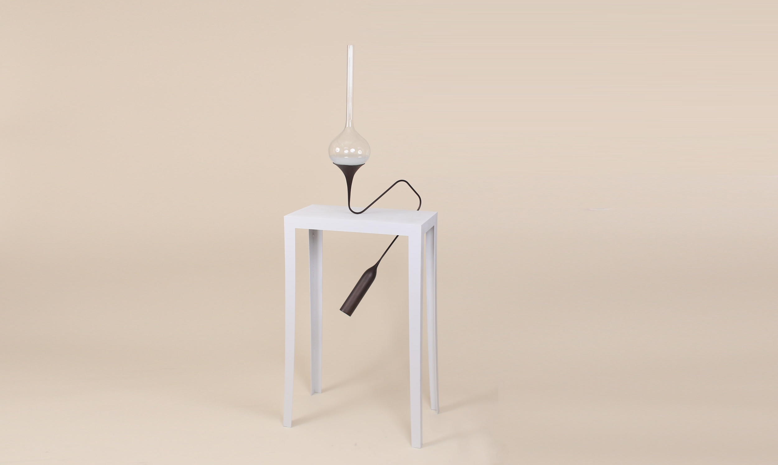 TEND is a tabletop light. In order to turn it on, nudge the lamp enough to make the seawater inside the glass vessel turbulent. The turbulent water will then illuminate and glow bright until the cast bronze ballast sways to a stop.