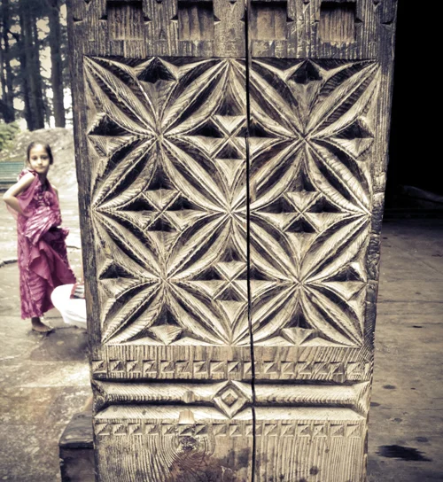 Detail of pillar carvings and young girl at the temple entrance 