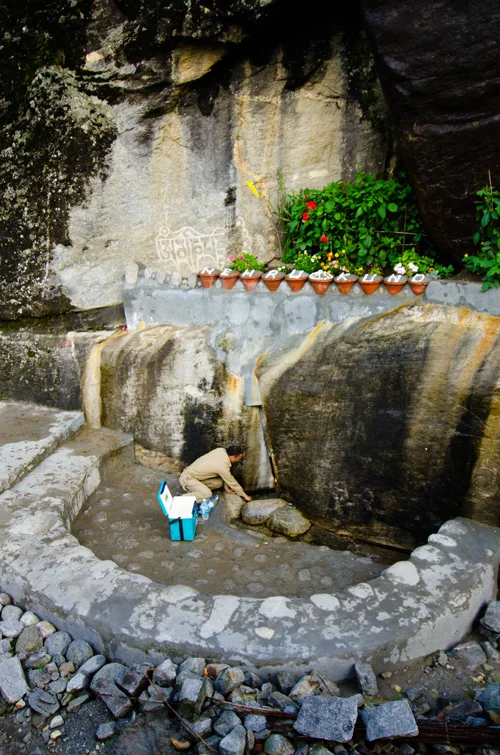 One of our drivers filling up their water bottles at a spring at the start of the journey in Manali