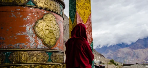 Monk by the prayer wheel outside the quiet gompa at Hunder