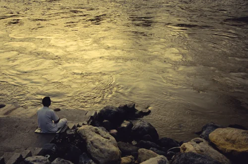 A man meditates in the evening by the river