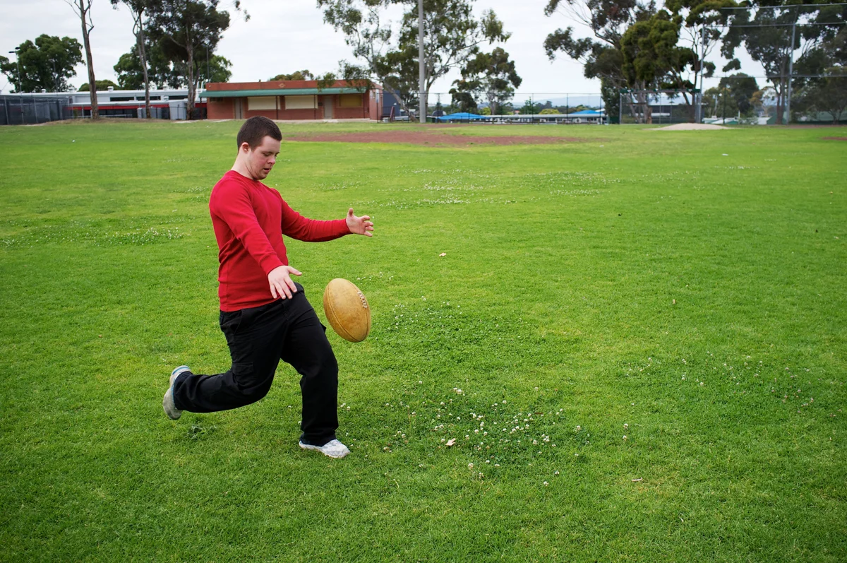 20111212-sixteen-year-old boy kicking football at a suburban park.jpg
