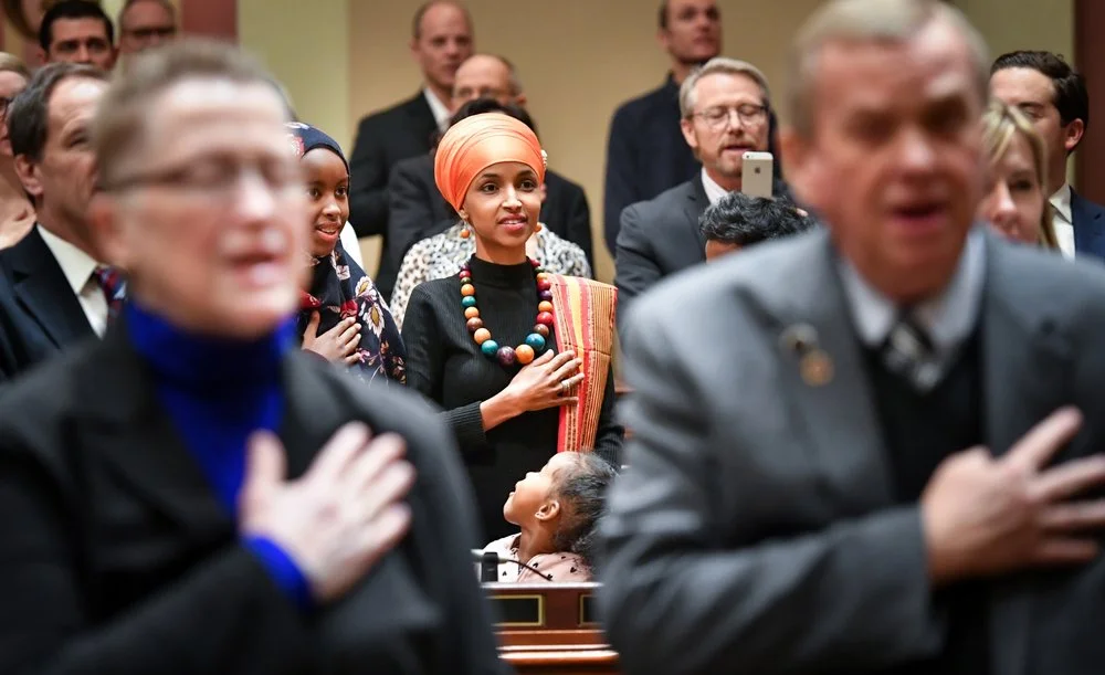 Ilhan stands surrounded by her young children as they share in her proud moment