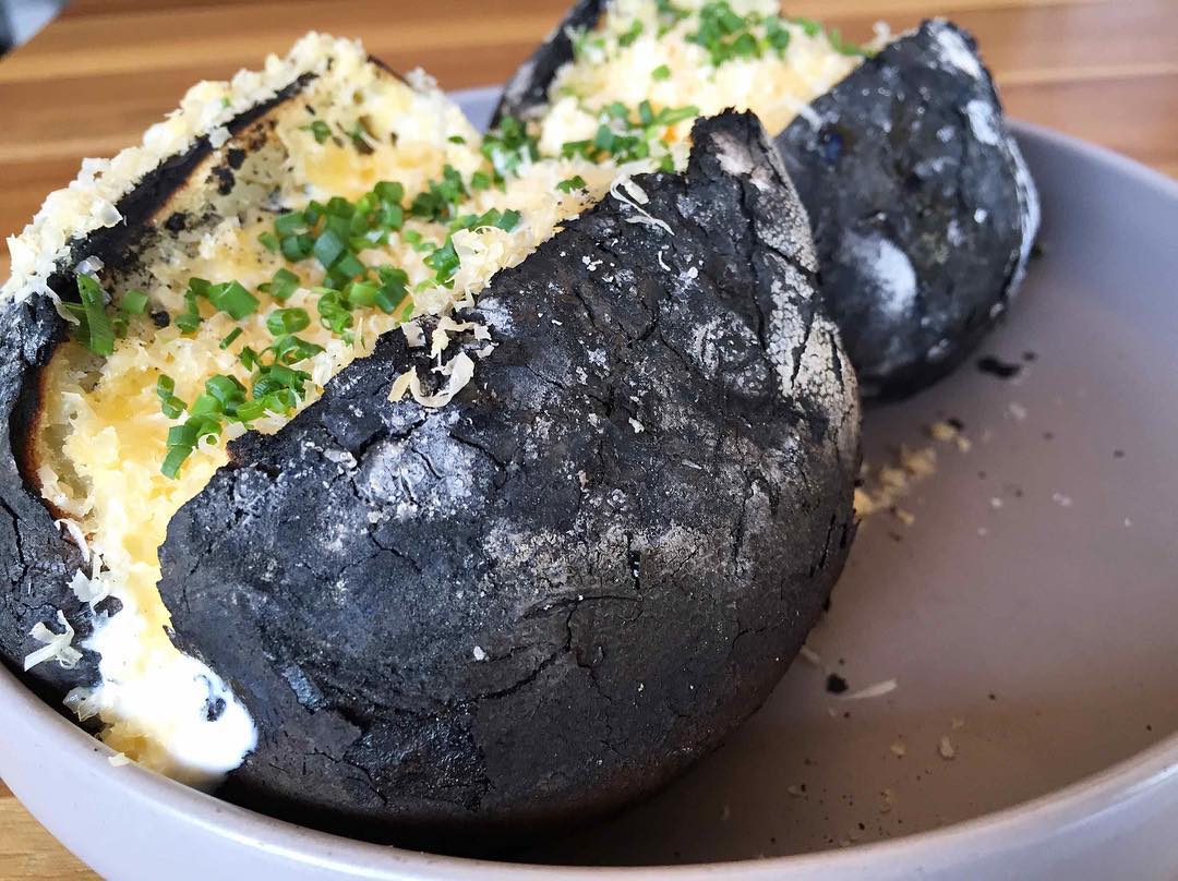 A side of potatoes baked in the coals and topped with creme fraiche, aged Gouda, and chives. Photo by Charcoal Venice