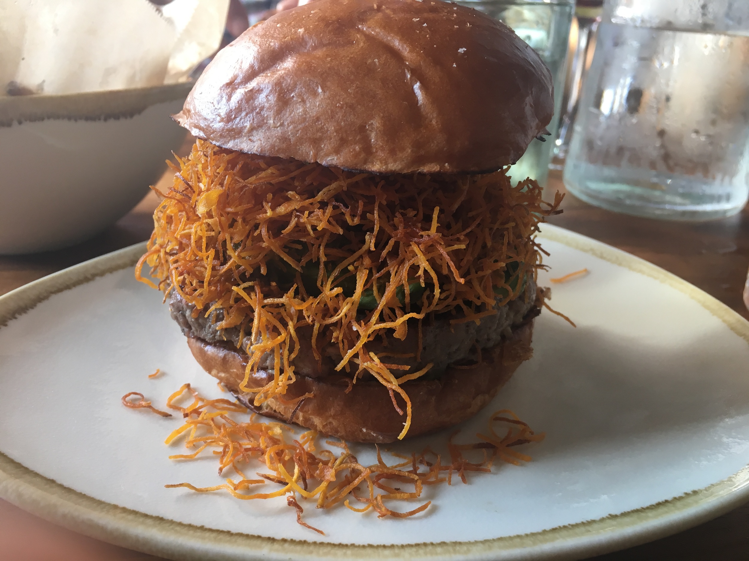 Pono Burger's Alekina from the seasonal menu, which gets a flavor boost from chorizo, chimichurri, and avocado, and its good looks from a sizeable “nest” of sweet potato straws. ( Photo by Erin Behan )