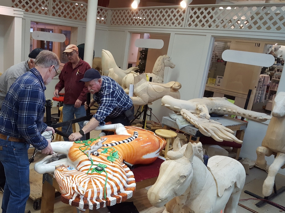 From the Albany, Oregon Carousel carving studio: volunteers fitting Quigga the Quagga for stirrups. ( Photo by Robin Murez )