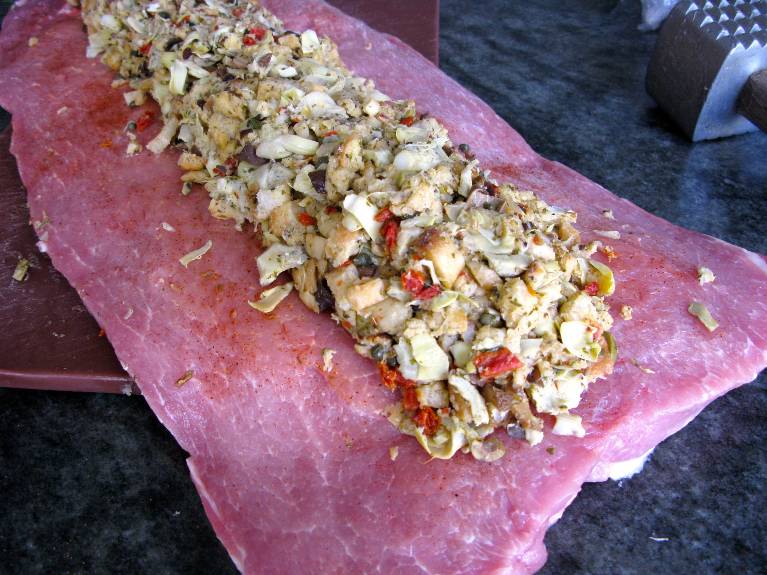 Placing the stuffing in the center of the butterflied pork loin.