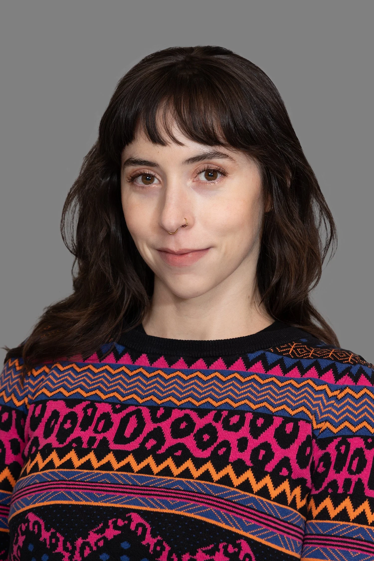 A picture of Charlotte on a gray background, wearing a fun sweater.