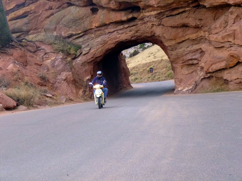 A biker ride through a rock tunnel in Morrison at Red Rocks Ampitheatre.