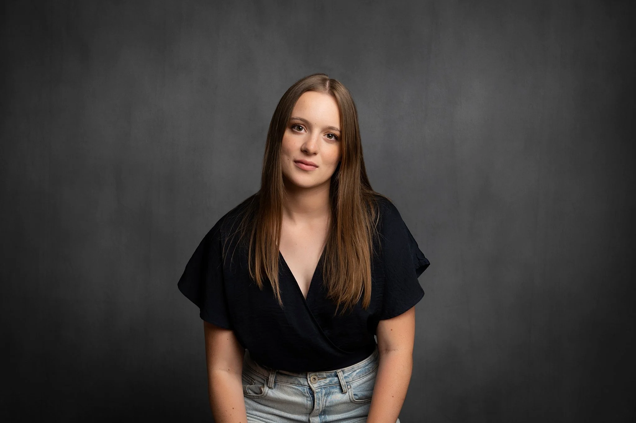 Close headshot of a woman with a confident, direct gaze on a dark studio background