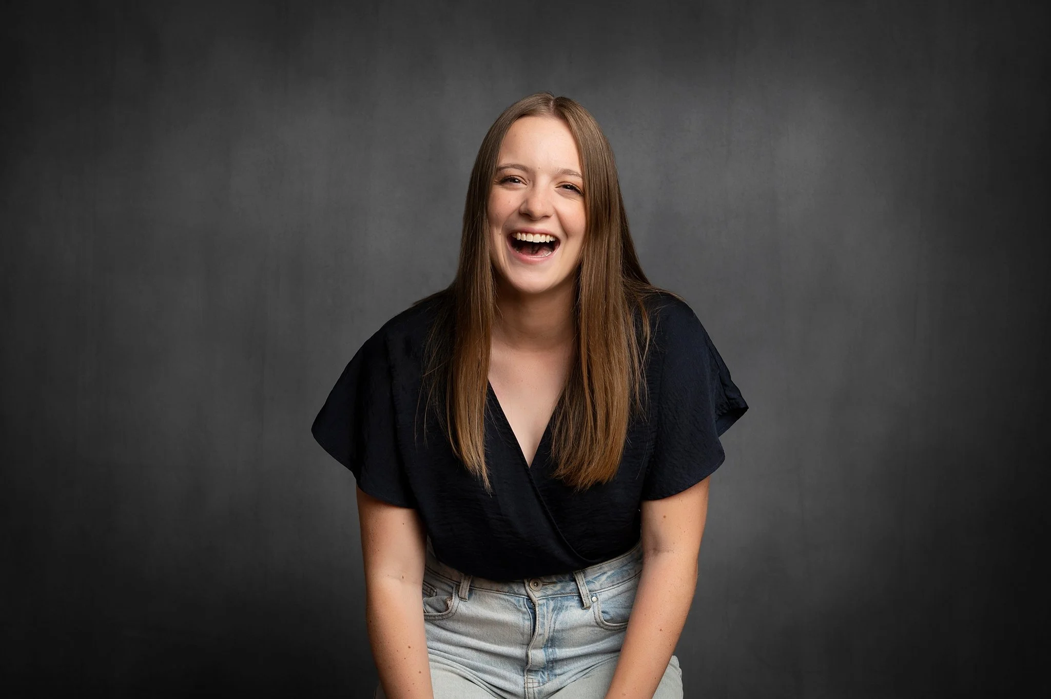 Woman laughing naturally during her headshot session at my North Shore studio, dark background